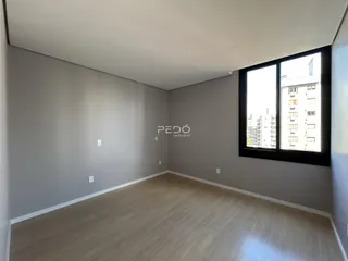 Ambiente interno de uma sala com piso de madeira e grande janela.