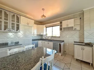 Cozinha e sala de jantar com armários brancos e piso de cerâmica.