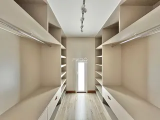 Hall de entrada com estantes embutidas e piso de madeira clara.