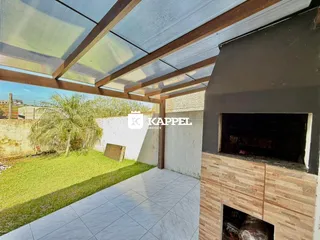 Vista de uma área externa coberta com piso de porcelanato e jardim.