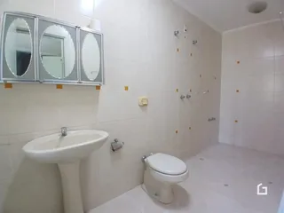 Foto de um banheiro com revestimento cerâmico branco e louças sanitárias.