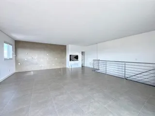 Ambiente interno de uma sala ampla com piso de cerâmica cinza.