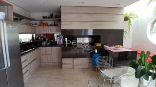 Cozinha moderna com armários e bancadas escuras em um imóvel no Brasil.