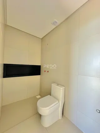 Foto de um banheiro com revestimento branco e piso claro.