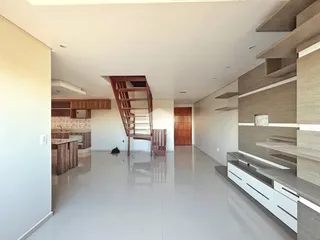 Vista de um corredor moderno com piso claro e escadaria de madeira.