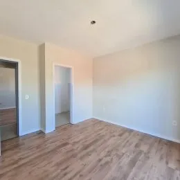 Ambiente interno com piso de madeira e paredes brancas.