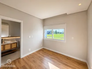 Sala de estar com piso de madeira e janela com vista para o campo.