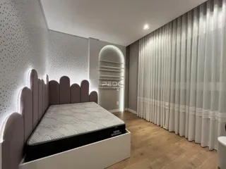 Quarto com cabeceira estofada e cortinas longas em ambiente claro.