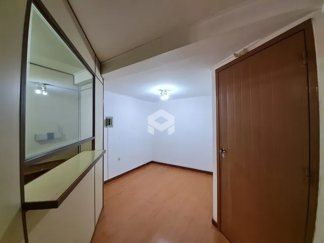Hall de entrada com piso de madeira e porta de madeira na residência.