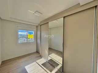Interior de um ambiente com piso de madeira e grande janela.