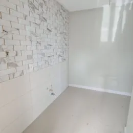 Vista parcial de uma parede revestida com azulejos brancos em um ambiente interno.