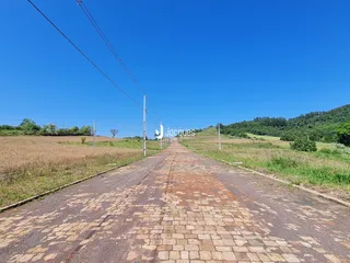 Uma estrada de tijolos se estende por uma paisagem de campo sob um céu azul.