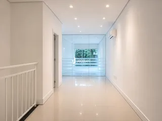 Corredor interno de um imóvel moderno com piso de cerâmica branco.