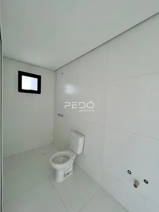 Foto de um banheiro interno com piso branco e vaso sanitário.