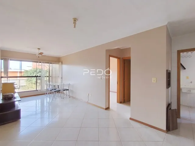 Sala de estar com piso de cerâmica clara e grandes janelas.