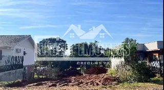 Vista externa de uma propriedade com vegetação e cerca no primeiro plano.
