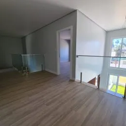 Vista interna de um ambiente com piso de madeira clara e uma área de sacada.