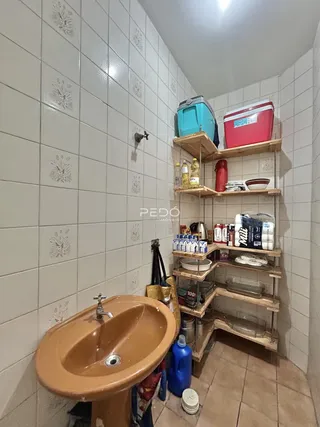 Banheiro com revestimento de azulejos brancos e pia de cor terracota.