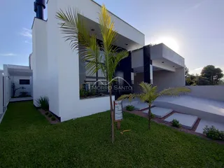 Fachada moderna de uma casa em Lajeado com jardim gramado e palmeiras.