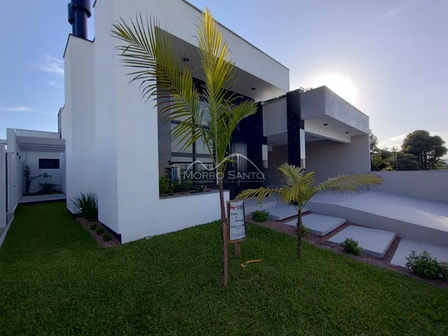 Fachada moderna de uma casa em Lajeado com jardim gramado e palmeiras.