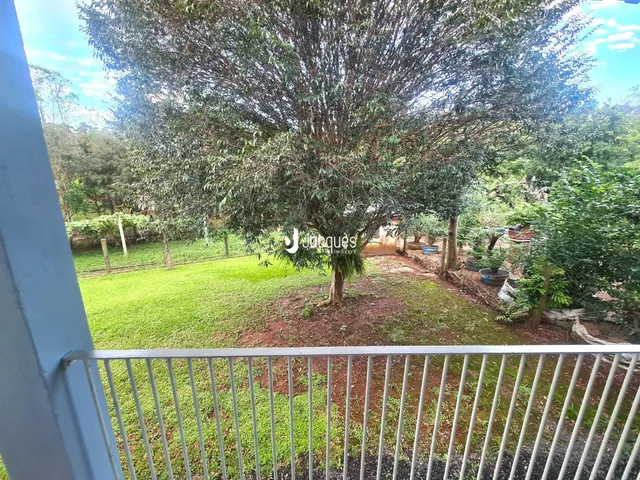 Vista externa de um jardim com gramado verde e árvores em Lajeado.