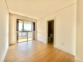 Sala de estar com piso de madeira e porta de vidro abrindo para a vista externa.