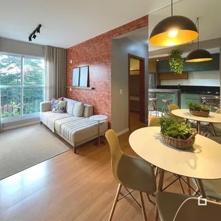 Sala de estar com piso de madeira e parede de tijolos vermelhos em Lajeado.