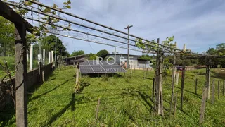 Campo gramado cercado por postes de madeira e arame.