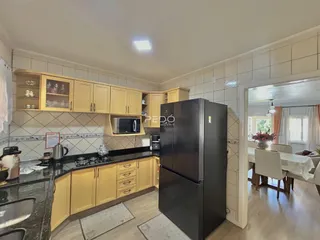 Imagem de uma cozinha com armários amarelos e bancadas escuras em Lajeado.