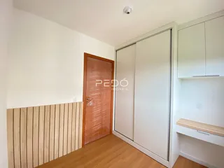 Interior de uma sala com piso de madeira e armários embutidos.