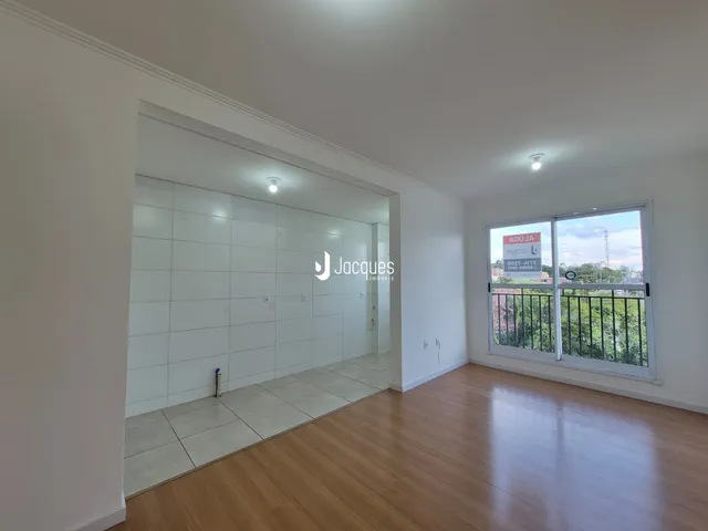 Interior de uma sala com piso de madeira e paredes brancas.