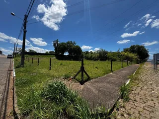 Vista externa de um campo gramado com caminho de terra ao lado de uma estrada.