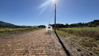 Uma estrada pavimentada leva a um campo aberto com colinas ao fundo.