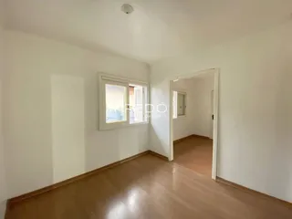 Vista interna de um ambiente com piso de madeira e paredes brancas.