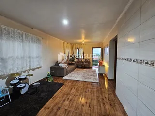 Uma sala de estar com piso de madeira e cortinas claras.
