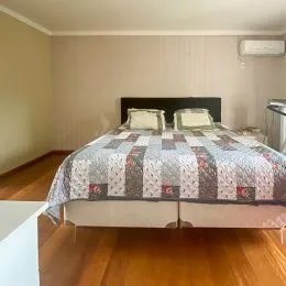 Quarto com cama de casal e piso de madeira.