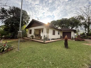 Vista externa de uma casa térrea com jardim gramado.