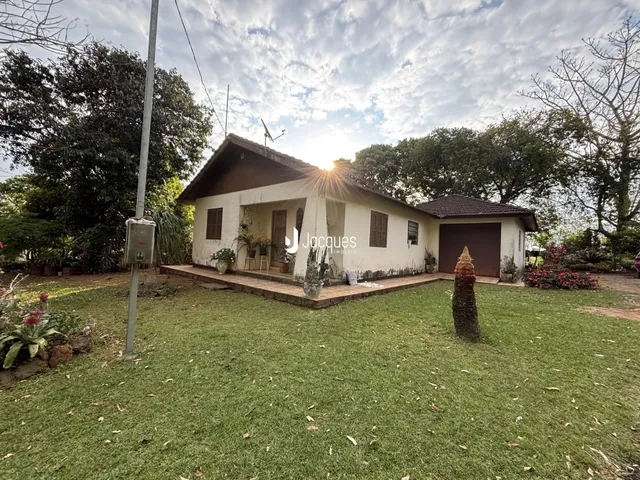 Vista externa de uma casa térrea com jardim gramado.
