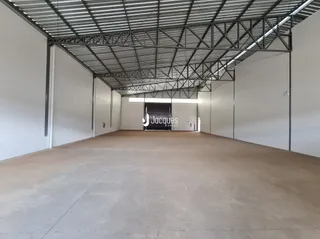 Vista interna de um espaço com estrutura metálica e piso de concreto.