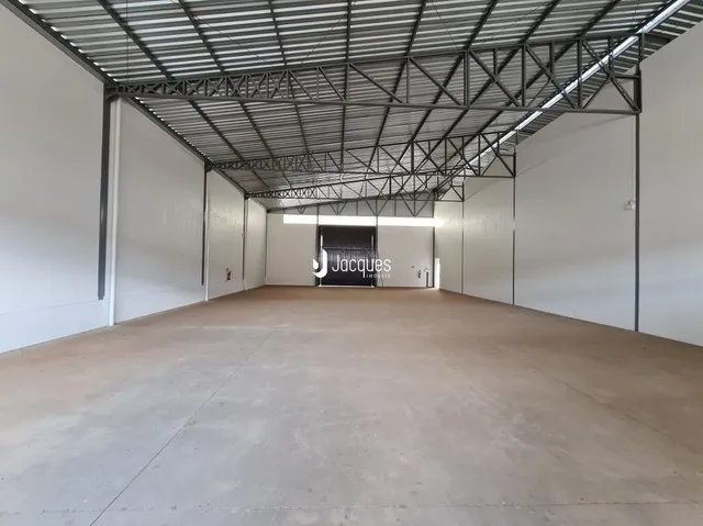 Vista interna de um espaço com estrutura metálica e piso de concreto.