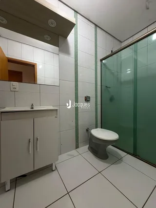 Foto de um banheiro com revestimento cerâmico e box de vidro.