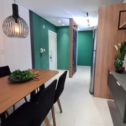 Mesa de madeira com cadeiras em um ambiente interno com paredes verdes.