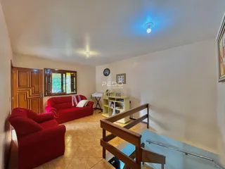 Sala de estar com dois sofás vermelhos e piso de cerâmica.