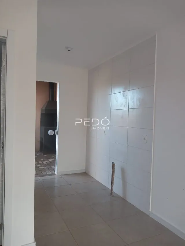 Hall de entrada com paredes brancas e piso de cerâmica em um imóvel.