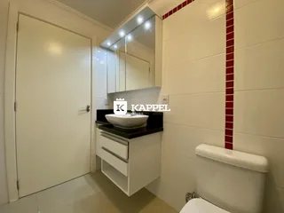 Banheiro com bancada branca e revestimento de azulejos brancos.