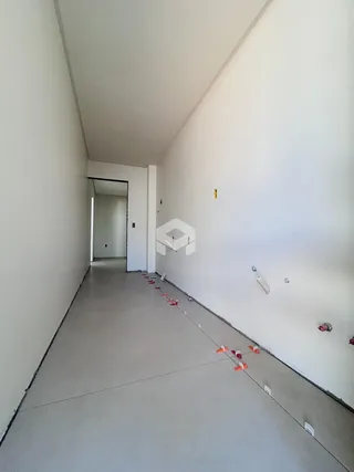 Corredor interno de uma residência com paredes brancas e piso em obra.