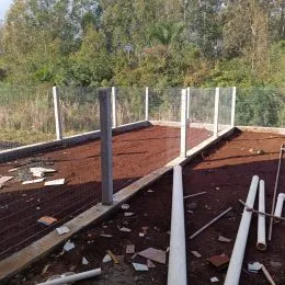 Foto de um terreno externo com terra e postes de sustentação.