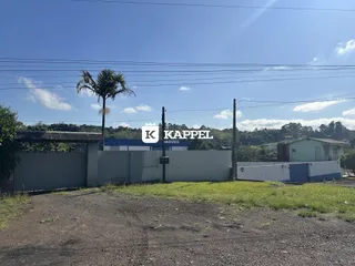 Vista externa da propriedade mostrando um muro de cerca e vegetação sob luz do dia.