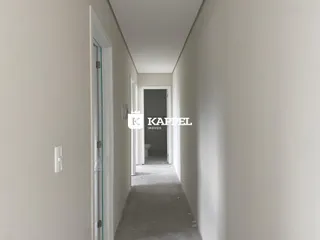 Corredor interno de uma residência com paredes brancas e porta ao fundo.