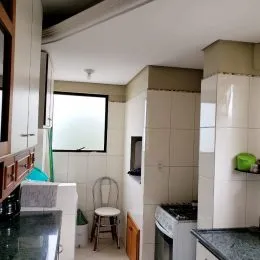 Foto interna de uma cozinha com armários brancos e bancada.